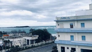 A hotel with a view of the sea, featuring a parking lot and a building with a blue and white facade.