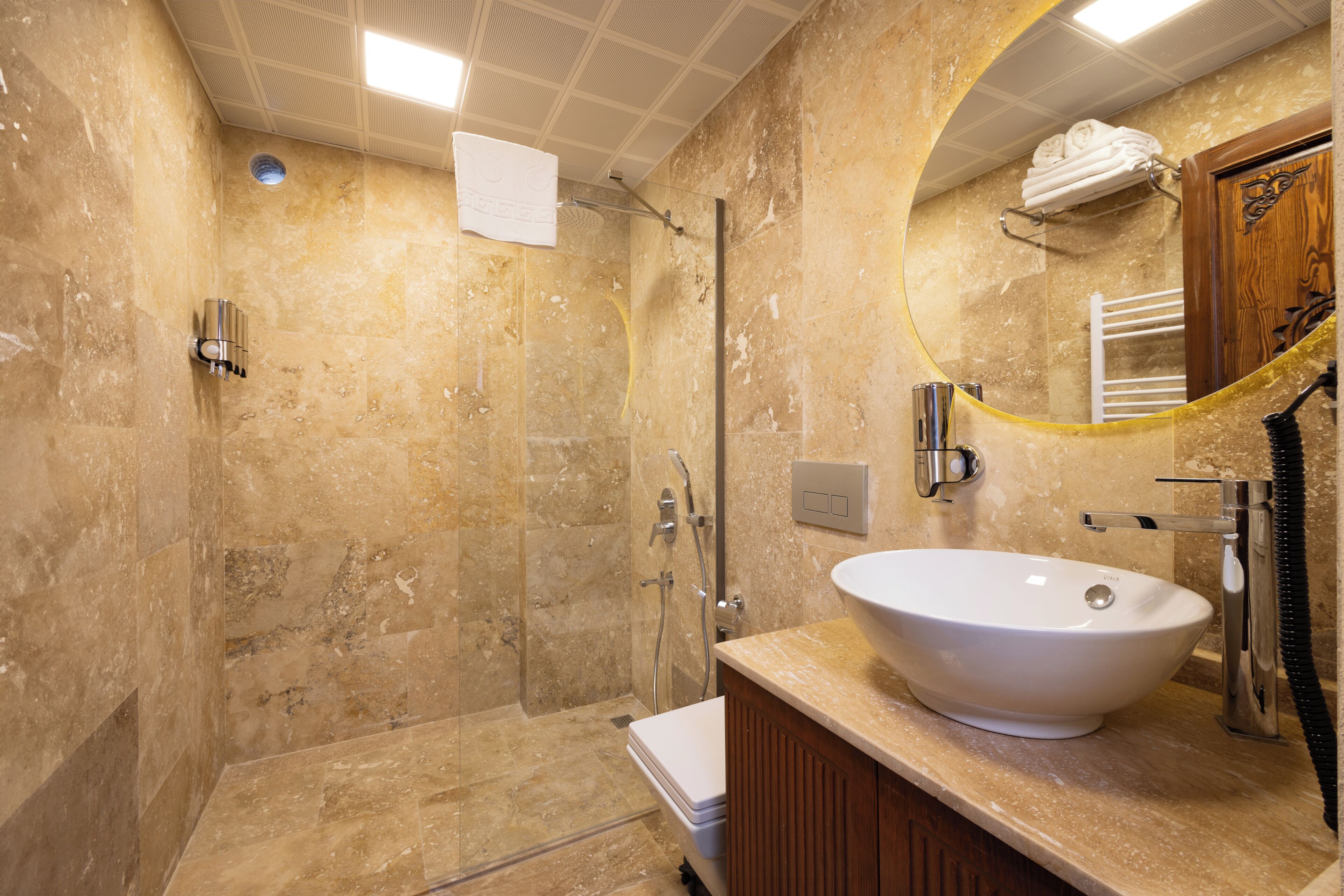 A bathroom with a large sink, a shower, and a mirror.