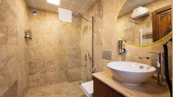 A bathroom with a large sink, a shower, and a mirror.