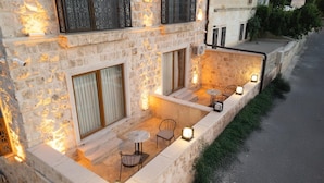 Un bâtiment en pierre doté d’un patio aménagé avec des espaces de détente en plein air et un éclairage extérieur.