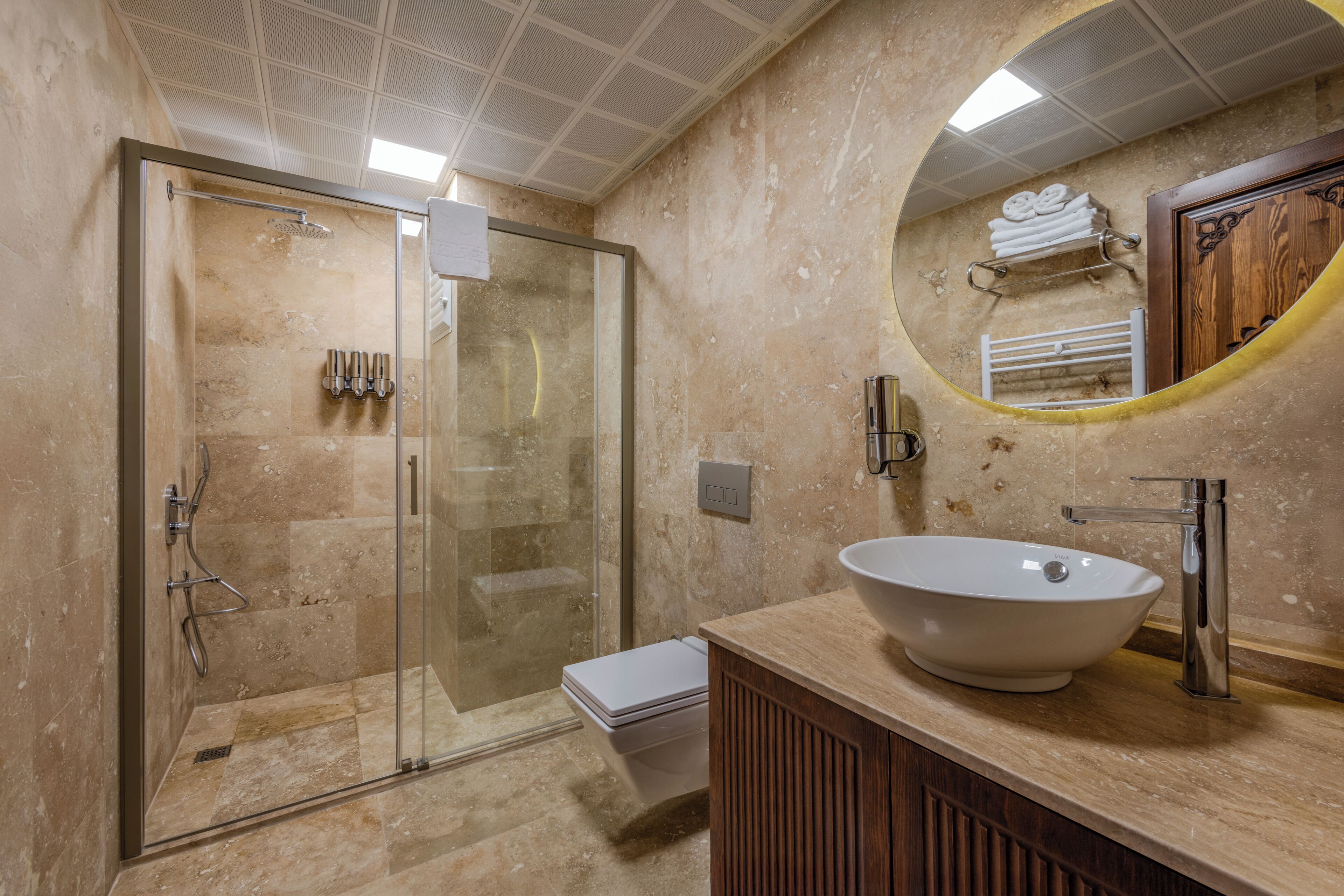 Une salle de bain moderne avec une douche à parois de verre, un lavabo blanc et un meuble-lavabo en bois.