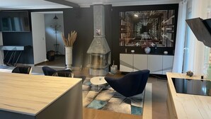 Ein modernes Wohnzimmer mit Kamin, Essbereich und einer Sitzecke mit Blick auf eine Stadtlandschaft.
