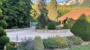 Ein angelegter Garten mit einem Pavillon, einem Kiesweg und verschiedenen Sträuchern und Bäumen.