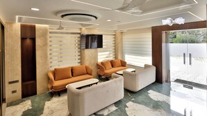 A modern living room with a sofa set, a flat-screen TV, and a ceiling fan. - Hotel Skyvista (Indore)
