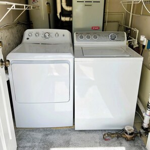 A laundry room with two front-loading washing machines and a water heater.