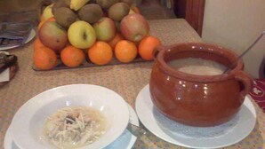 A table with a bowl of soup and a large clay pot on a patterned tablecloth. - Hotel La Botiga (Prades)