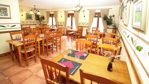 A dining area with multiple wooden tables and chairs, each set with cutlery and wine glasses. - Hotel La Botiga (Prades)
