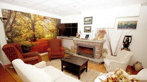 A living room with a fireplace, a large painting, and a television. - Hotel La Botiga (Prades)