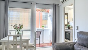 A modern living room with a sofa, a dining table with chairs, and a view of the outside balcony. - Central Apartment with Balcony in Estepona (Estepona)