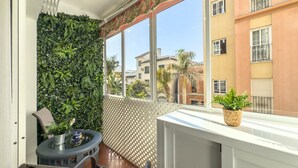 A balcony with a green wall, a table with chairs, and a view of neighboring buildings. - Central Apartment with Balcony in Estepona (Estepona)
