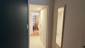 A narrow hallway with a door leading to a room with a bed and a chair. - Jungle Studio with Terrace and Heated Pool near Nantes (Port-Saint-Père)