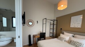 A bedroom with a bed, a bedside table, a mirror, a hanging light fixture, a wall-mounted shelf, and a framed picture. - Jungle Studio with Terrace and Heated Pool near Nantes (Port-Saint-Père)