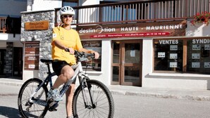 A person on a bicycle in front of a building with a sign that reads "Destination Haute - Maurienne". - Aussois apartment for 6 with balcony and internet access (Aussois)