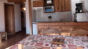 A compact kitchen with wooden cabinets, a microwave, a coffee maker, and a sink.