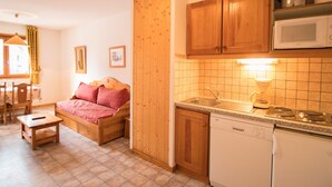 A compact kitchen with wooden cabinets, a microwave, and a dishwasher. - Cozy apartment with parking, sleeps 4, near shuttles in Aussois (Aussois)