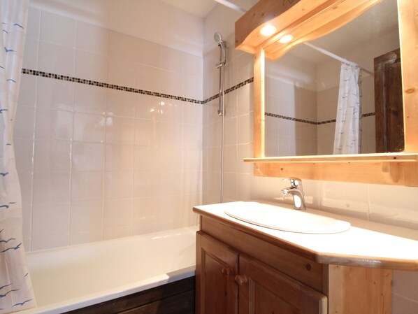 Un baño con bañera, tocador de madera y espejo.