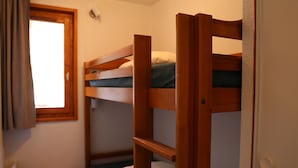 A bunk bed room with a small wooden table and a window with curtains. - Comfortable apartment in Aussois for 6 with terrace (Aussois)