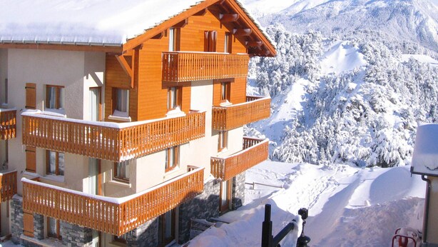 A multi-story chalet with wooden balconies and a view of snow-covered mountains. - Comfortable apartment in Aussois for 6 with terrace (Aussois)