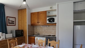 A compact kitchen with wooden cabinets, a microwave, a sink, and a refrigerator. - Comfortable apartment in Aussois for 6 with terrace (Aussois)