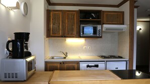 A compact kitchen with wooden cabinets, a microwave, a coffee maker, and a sink.