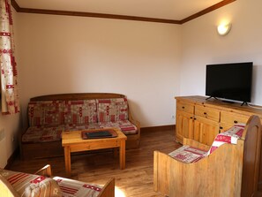 A cozy living room with a sofa, wooden coffee table, and a TV on a wooden cabinet.