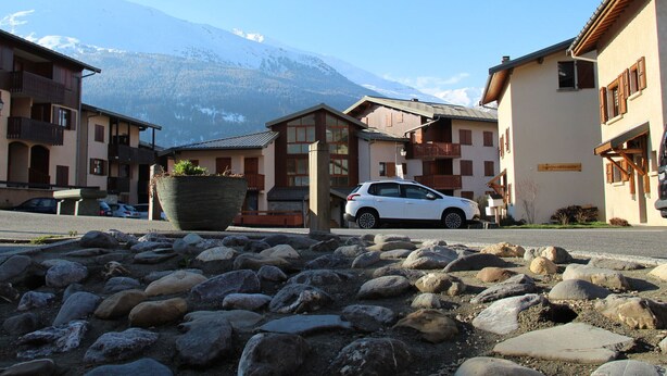 Una hilera de edificios tradicionales de montaña con un coche estacionado al frente.
