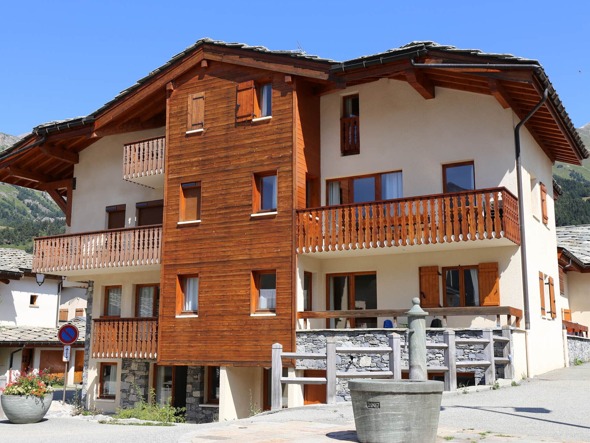 A multi-story building with wooden balconies, stone accents, and a clear sky.