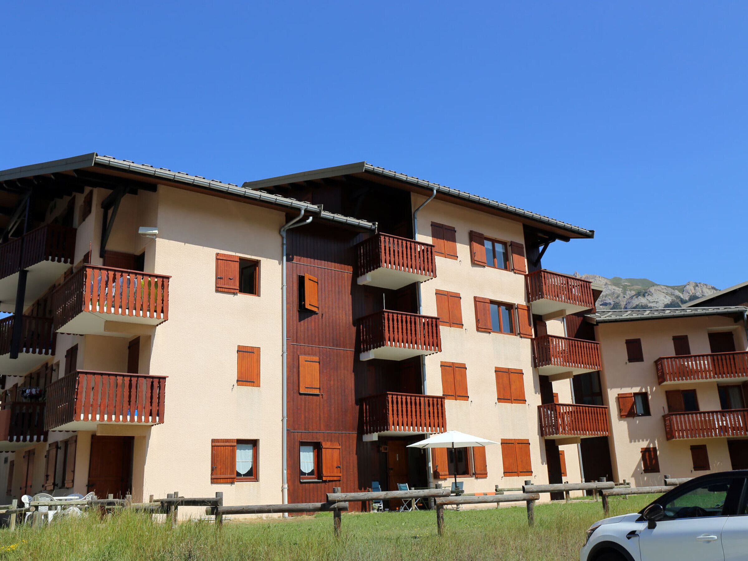 A multi-story building with balconies, a clear sky, and mountains in the background.