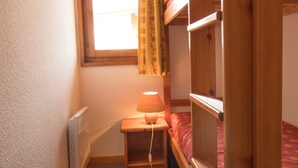 A small, cozy bedroom with a single bed, a bedside table with a lamp, and a window with curtains. - Quiet apartment in Aussois, near shuttles and leisure (Aussois)