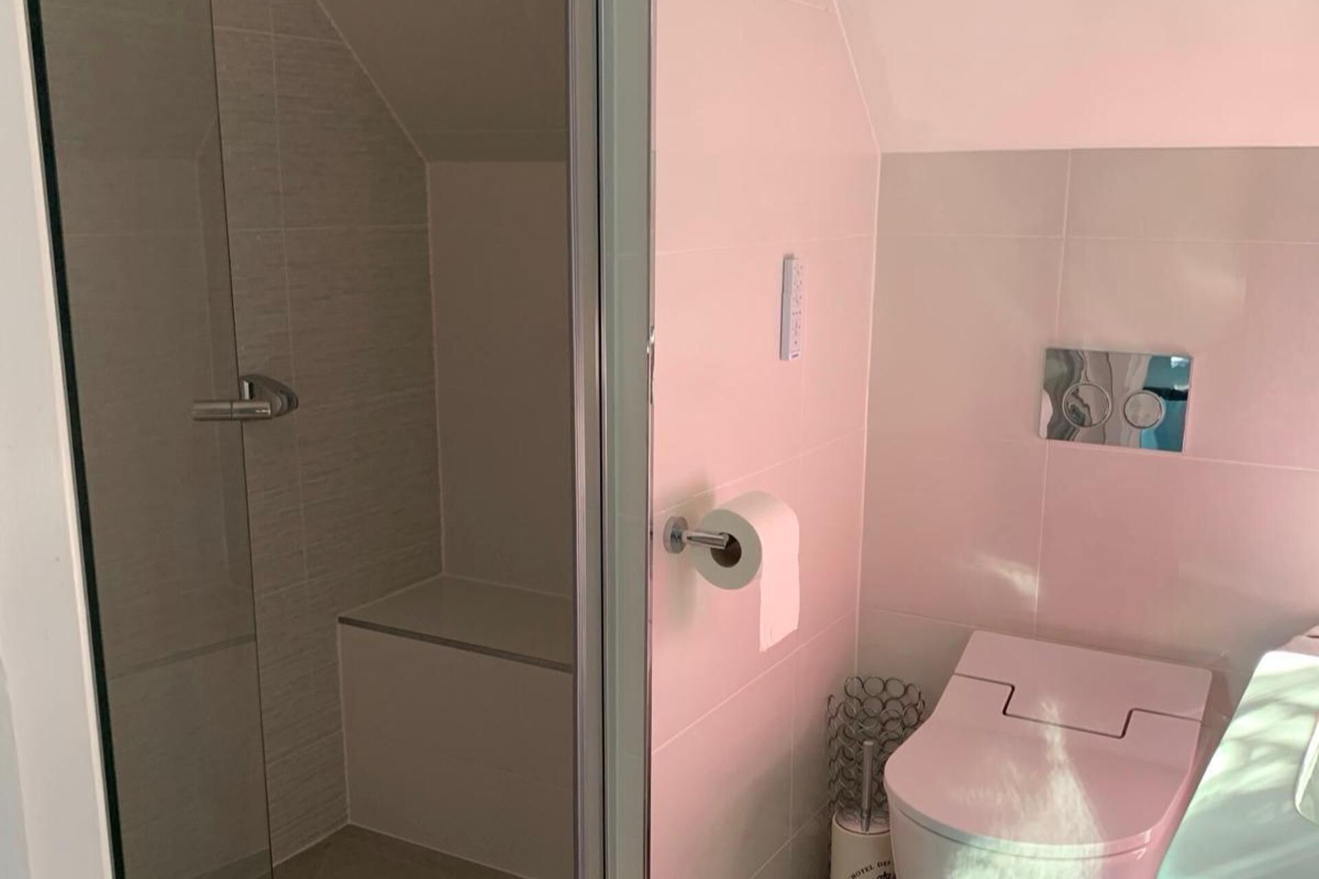 Et badeværelse med bruser, toilet og vask.