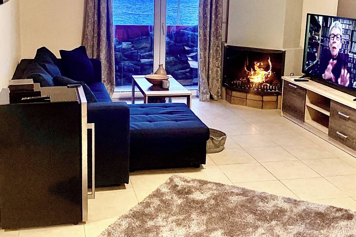 A living room with a sofa, a coffee table, a fireplace, and a television.
