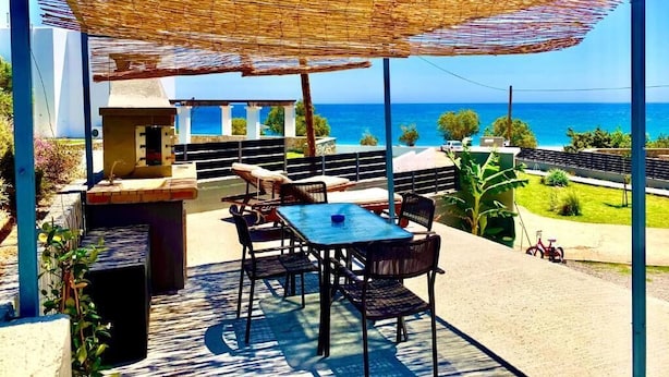 An outdoor patio with a table and chairs, a barbecue grill, and a view of the ocean. - Helios  Apartments (Rhodes)
