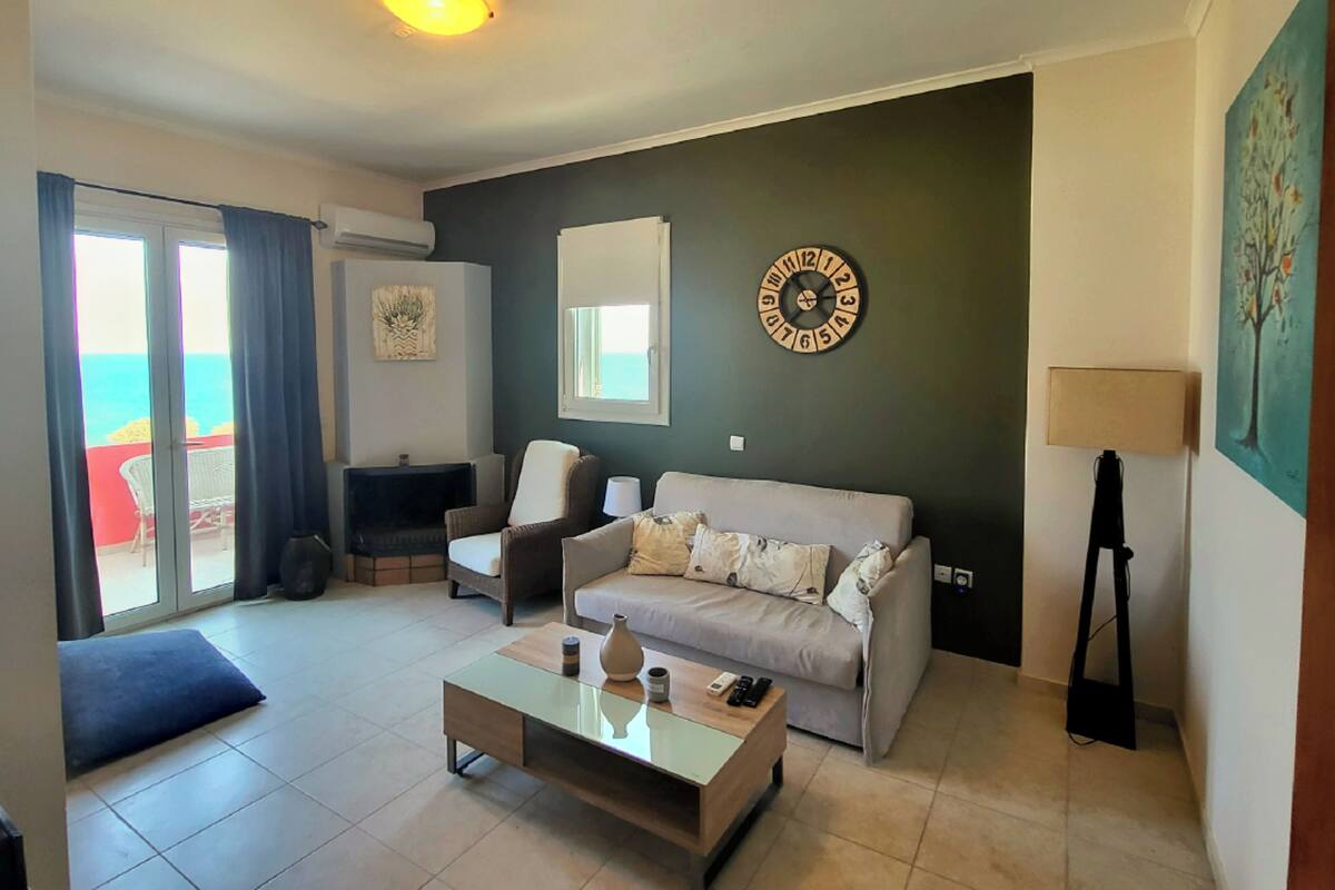 A living room with a sofa, armchairs, a coffee table, and a wall clock.