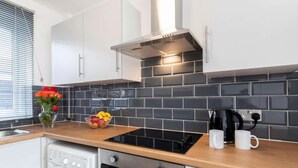 A modern kitchen with a black tiled backsplash, stainless steel appliances, a wooden countertop, and a washing machine. - 4 bedroom home in Billingham (Stockton on Tees)