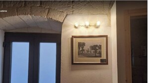 Une pièce avec une photographie en noir et blanc encadrée accrochée au mur, un plafond à la finition texturée et une porte dotée de panneaux en verre dépoli.