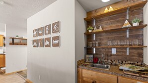 A kitchen with wooden cabinets, a granite countertop, and a backsplash with a mosaic tile pattern. - Grandma's Hideaway - walk to downtown, private hot tub, pet friendly with patio (McCall)