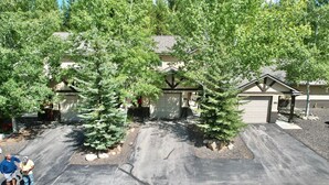 A residential driveway with two garage doors, surrounded by trees. - Grandma's Hideaway - walk to downtown, private hot tub, pet friendly with patio (McCall)