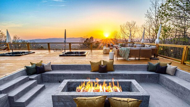 Een terras met vuurkorf, zitplaatsen en uitzicht op de ondergaande zon.