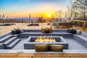 A deck with a fire pit, seating, and a view of the sunset. - 14k sq ft Mountaintop Estate - Private Golf Course (Fletcher)