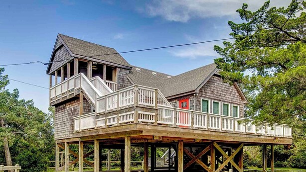A wooden house with a balcony and a red door, elevated on stilts. - Sandpiper Cottage - Ocracoke Island (Ocracoke)