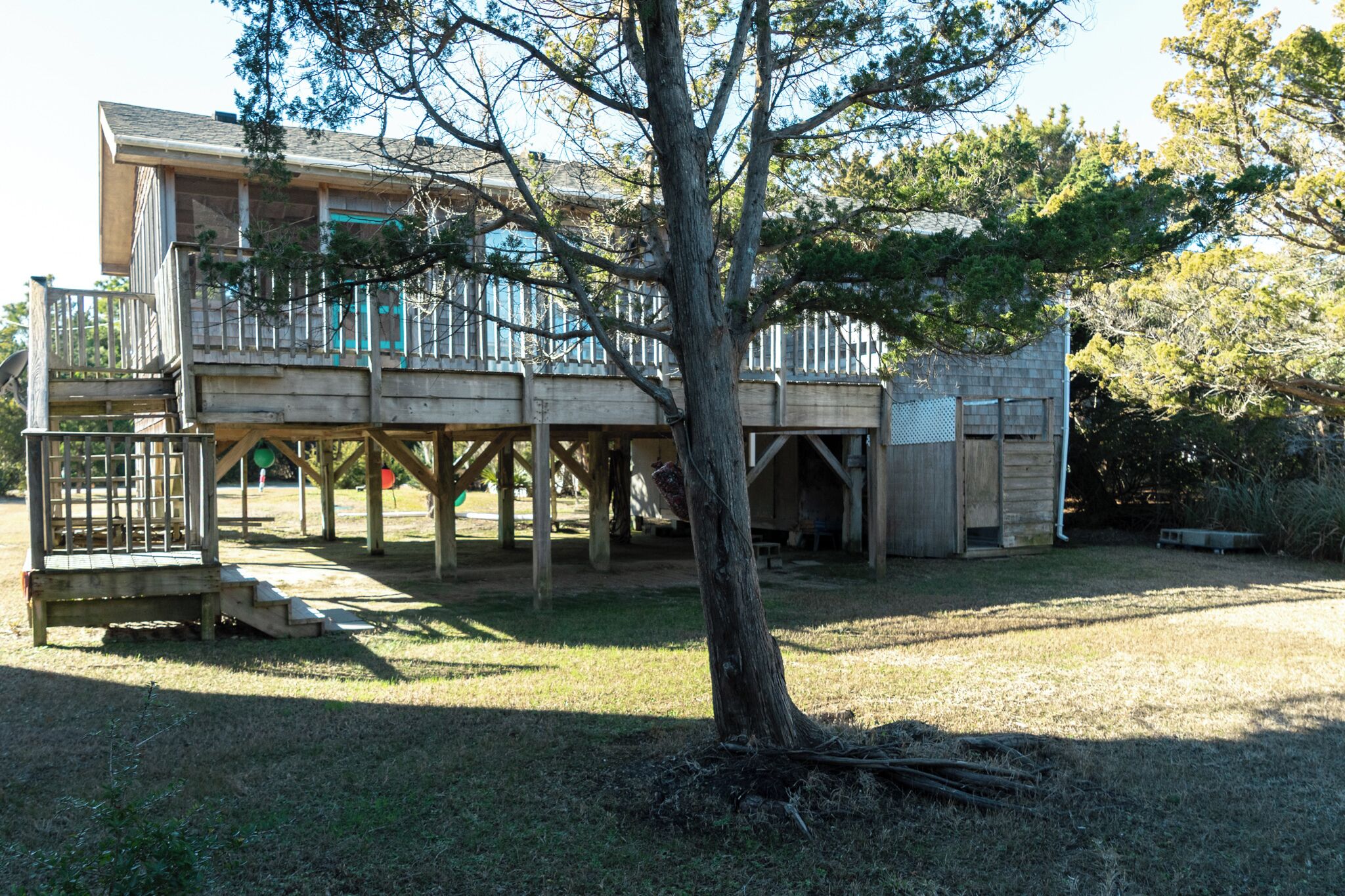 A two-story wooden house with a deck and a fenced play area.
