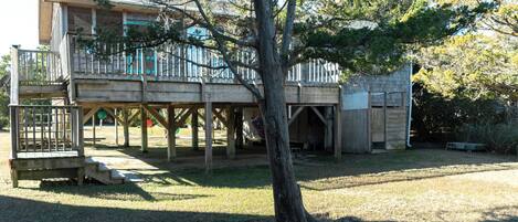 A two-story wooden house with a deck and a fenced play area.
