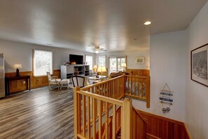 Relax in this spacious living area with a high ceiling, featuring a large flat-screen TV and comfortable seating for two.