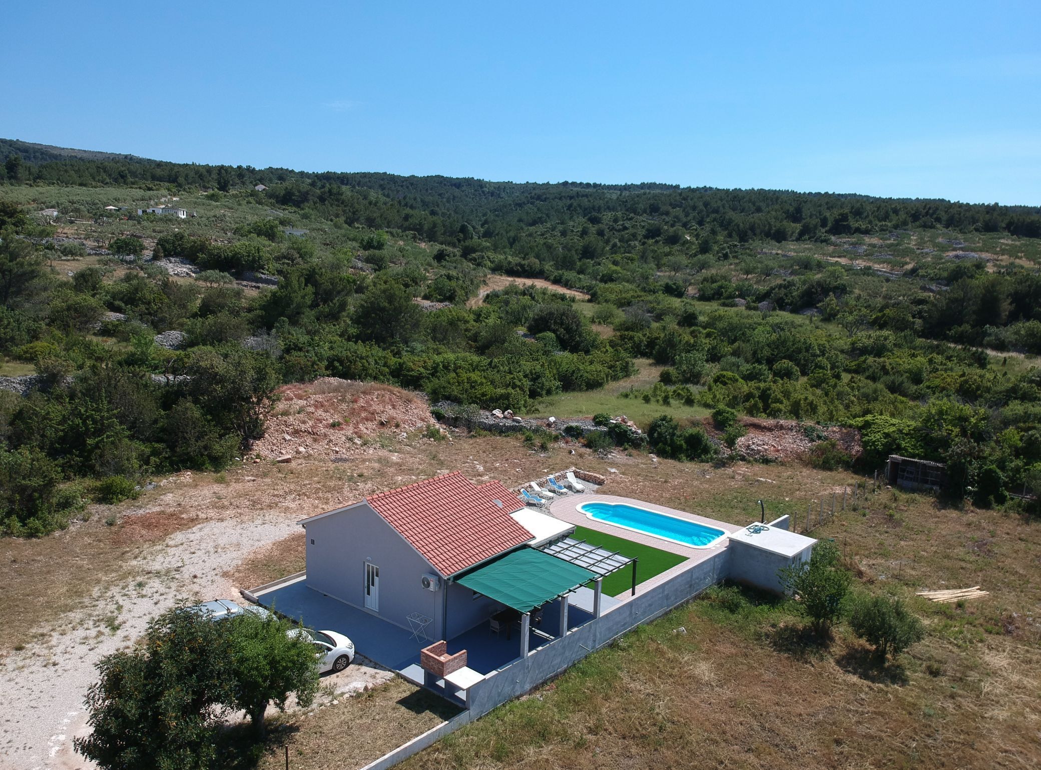 A house with a swimming pool, surrounded by a hilly landscape.