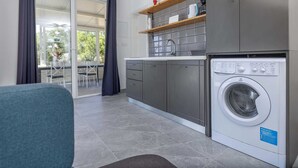 Eine kompakte Küche mit integrierter Waschmaschine, grauen Schränken und einem Essbereich mit Tisch und Stühlen.