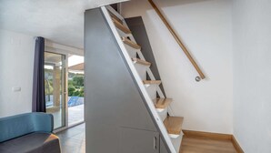 Ein modernes Interieur mit einer Treppe, einem blauen Sofa und einer Glastür, die nach draußen führt.