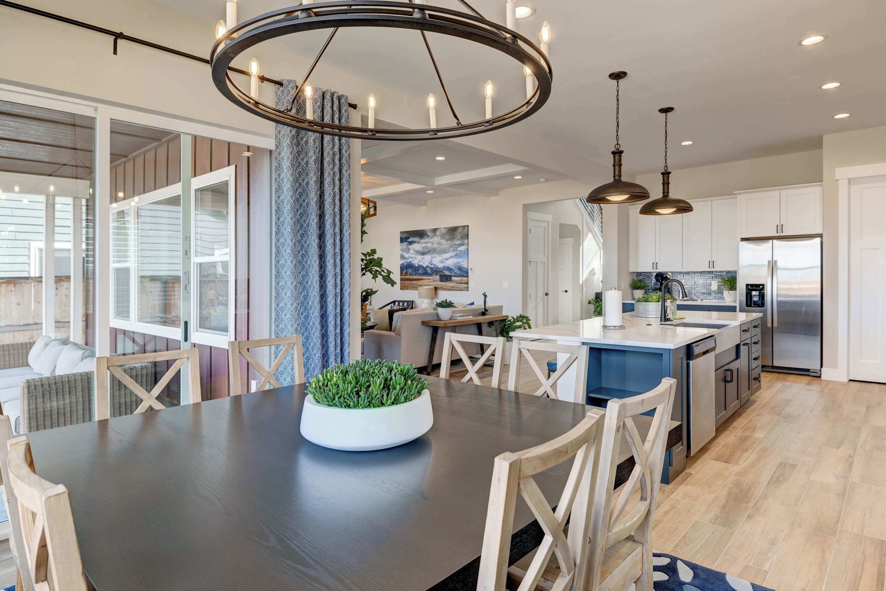 A modern kitchen with a central island, stainless steel appliances, and a dining area with a dark wooden table and light wood chairs.