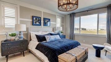 A bedroom with a large bed, a nightstand, a dresser, a bench, and a view of the outdoors.