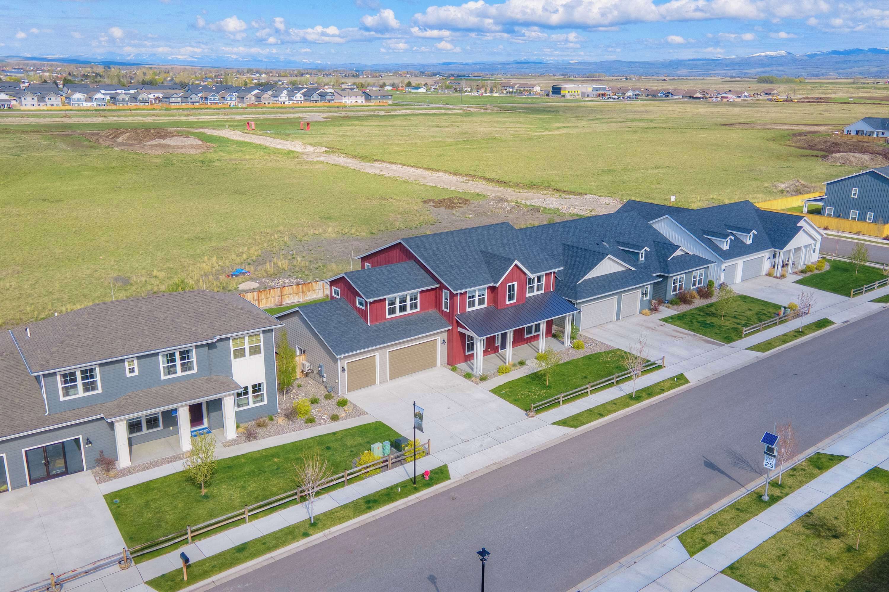 A residential area with houses, a clear road, and open fields.
