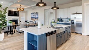 A modern kitchen with a central island, stainless steel appliances, and pendant lighting. - Spacious 4BR Retreat Near Bozeman (Belgrade)